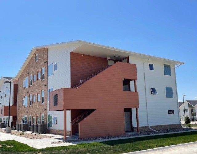 A large brick and white apartment building with stairs leading up to the second floor.