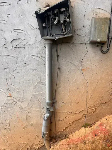 Damaged electrical box and conduit attached to a textured wall.
