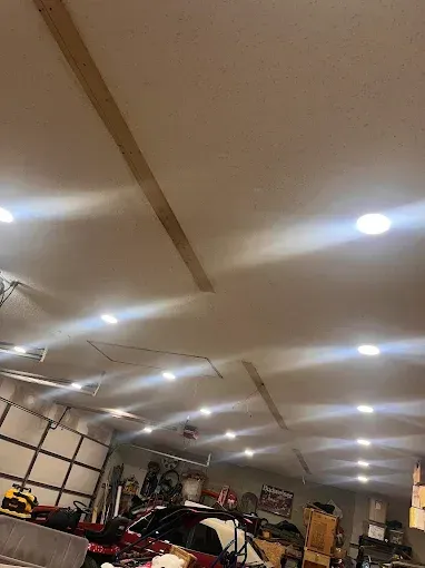 Garage interior with recessed lights illuminating a white ceiling. Wooden beams are visible.