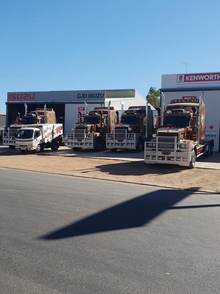 A Row of Trucks Parked in Front of a Building That Says Kenworth — Autofit88 Auto Electrics In Ciccone, NT