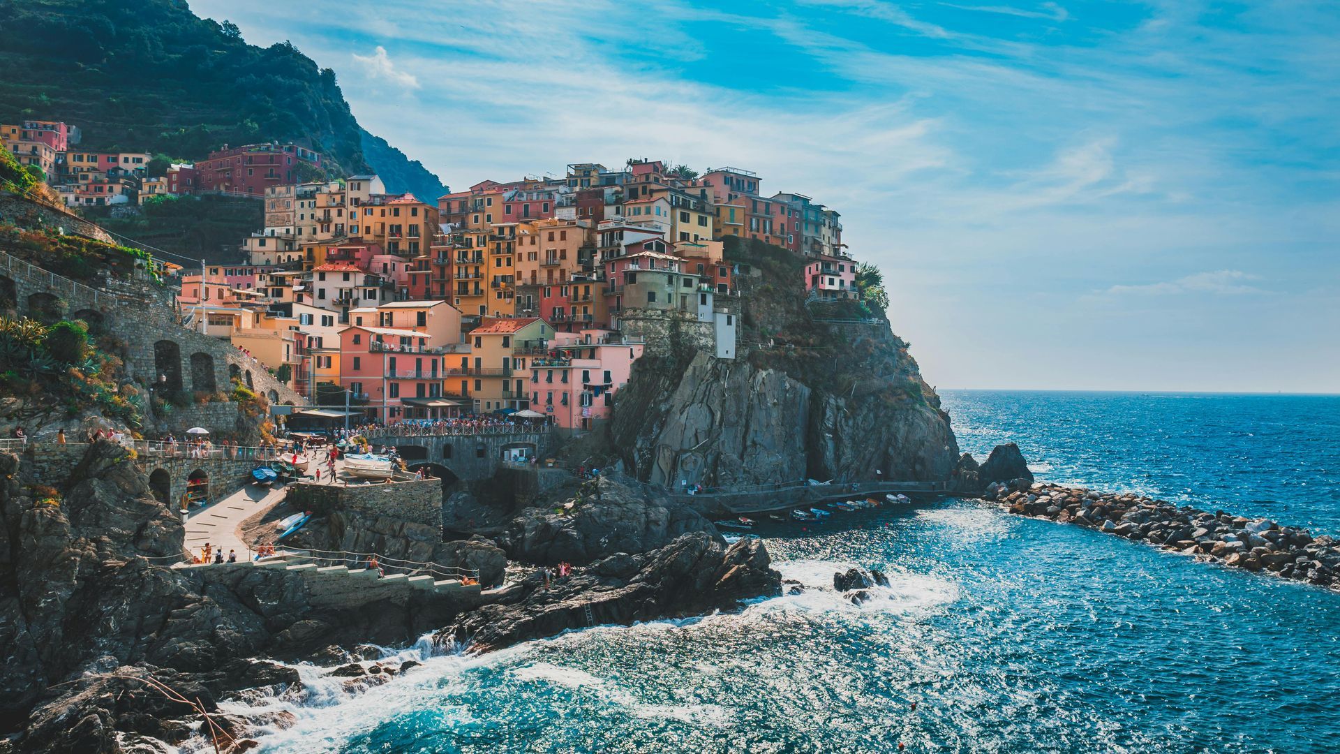 Colorful buildings perched on a cliffside by a blue sea.