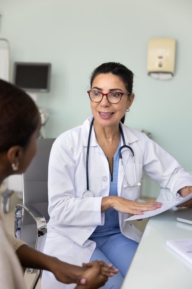 Doctor in lab coat discussing papers with patient in a clinic room.