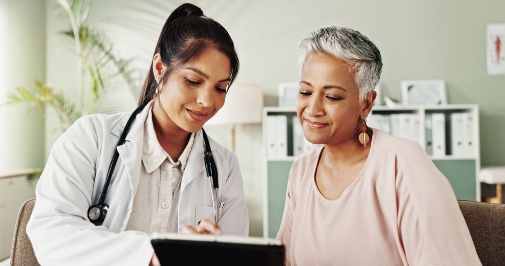 Doctor showing tablet to patient in a medical office. Both smiling, examining the screen.