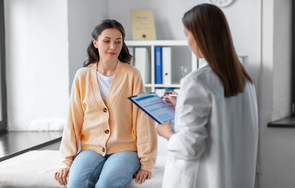 Patient speaking with a doctor in a bright clinic while the doctor reviews a tablet.