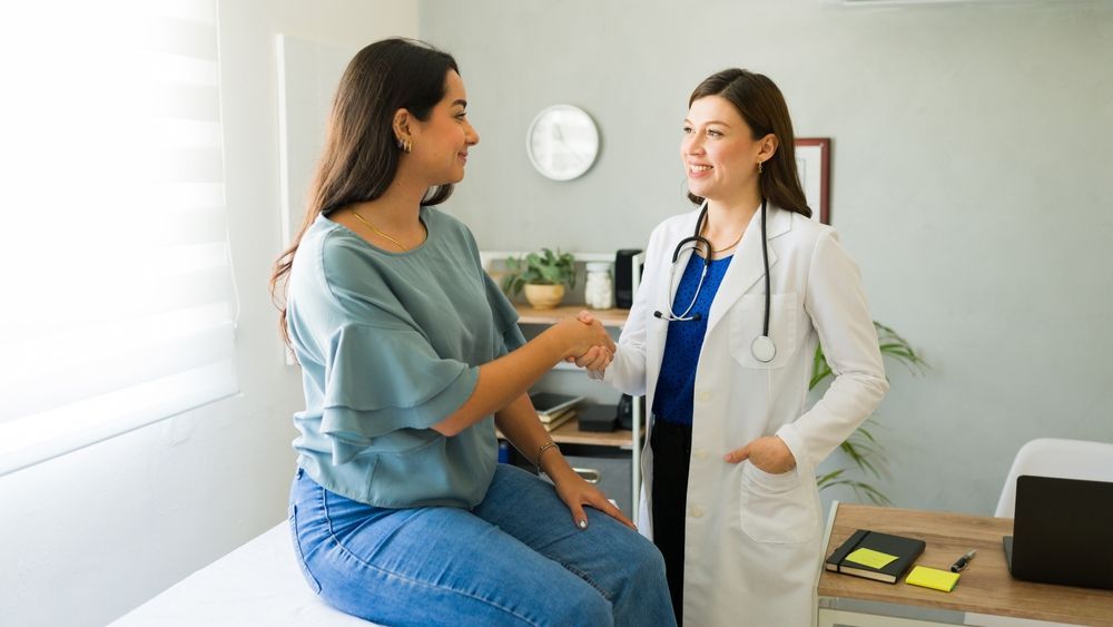 A doctor shaking hands with a patient in a doctor's office.