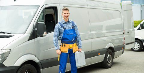 Young repairman with tools and toolbox standing in front of service van