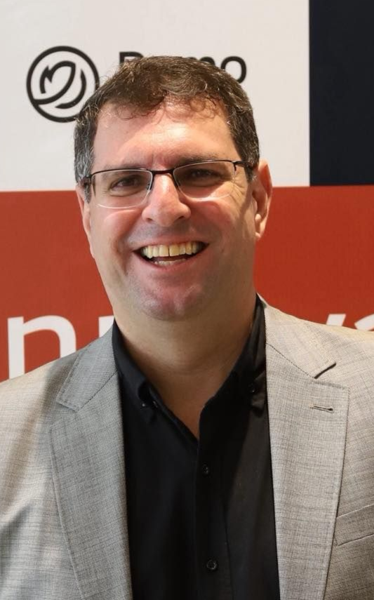 Um homem vestindo uma camisa listrada azul e branca está sorrindo para a câmera.