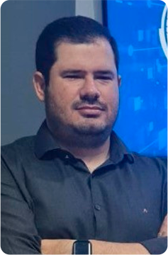 Um homem usando óculos e uma camisa azul sorri para a câmera