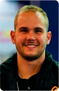 Um homem usando óculos e terno sorri para a câmera