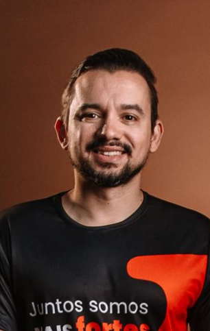 Um homem com barba está segurando um microfone e sorrindo.