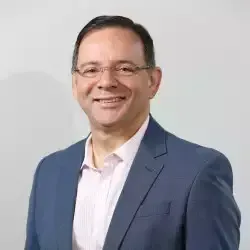 Um homem está falando em um microfone em frente a uma tela que diz itivologia