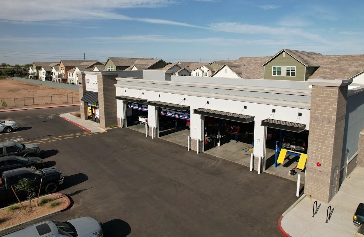 An aerial view of an AAMCO Transmissions & Total Car Care shop with multiple bays, adjacent to a residential area on a sunny day.
