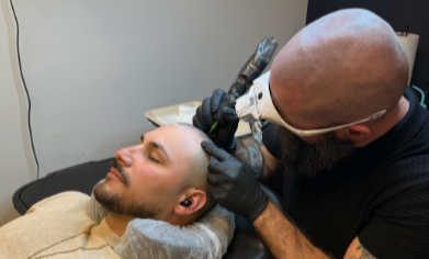 An SMP INK CDA Student Practitioner drawing the reference line on the scalp of  an SMP client in a class setting.