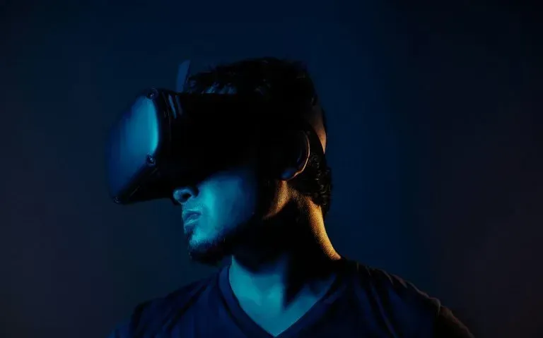 A man is wearing a virtual reality headset in a dark room.