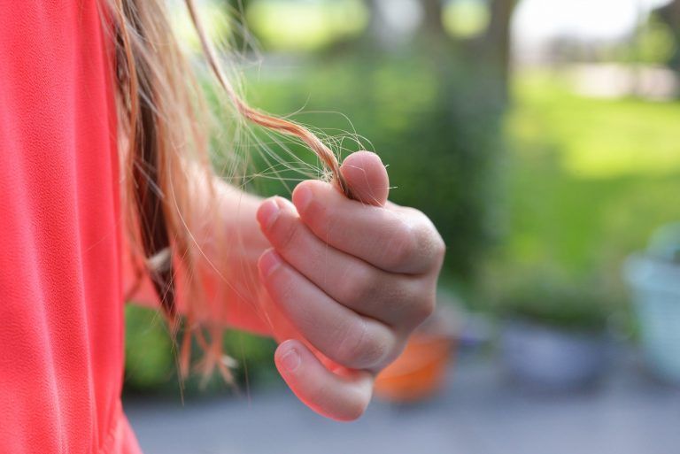 A person is holding a piece of hair in their hand.