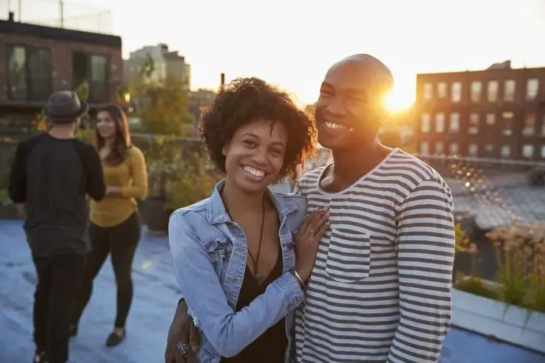 A man and a woman are posing for a picture on a rooftop.