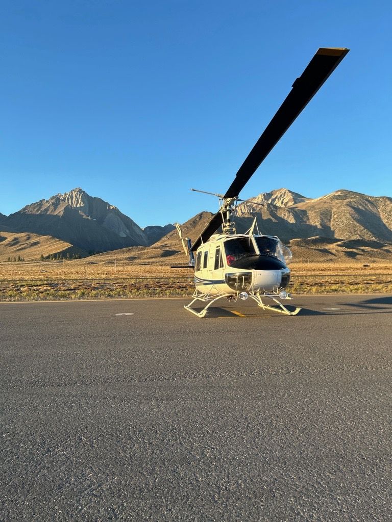 A helicopter is sitting on a runway with mountains in the background.