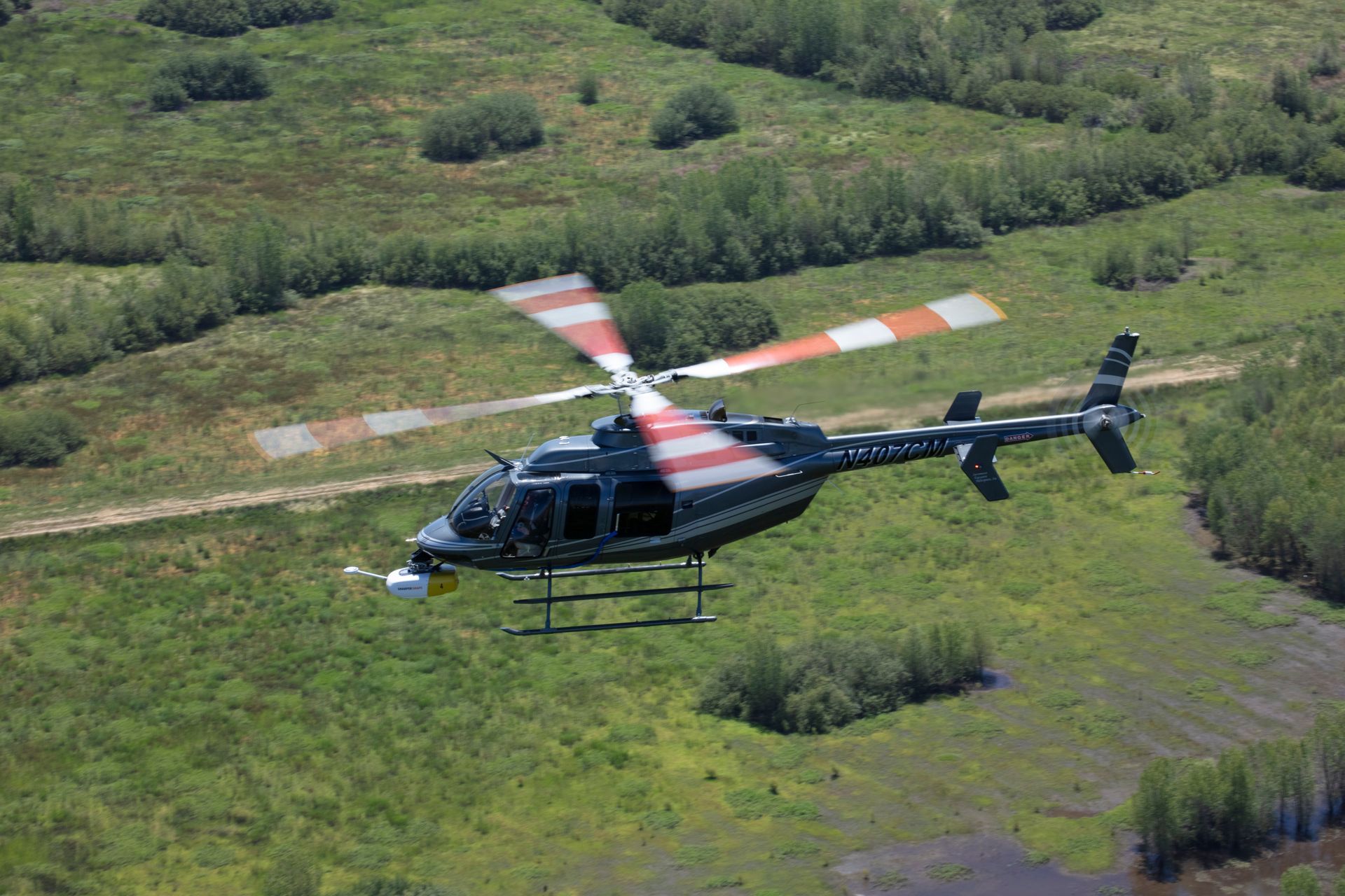 A helicopter is flying over a grassy field.