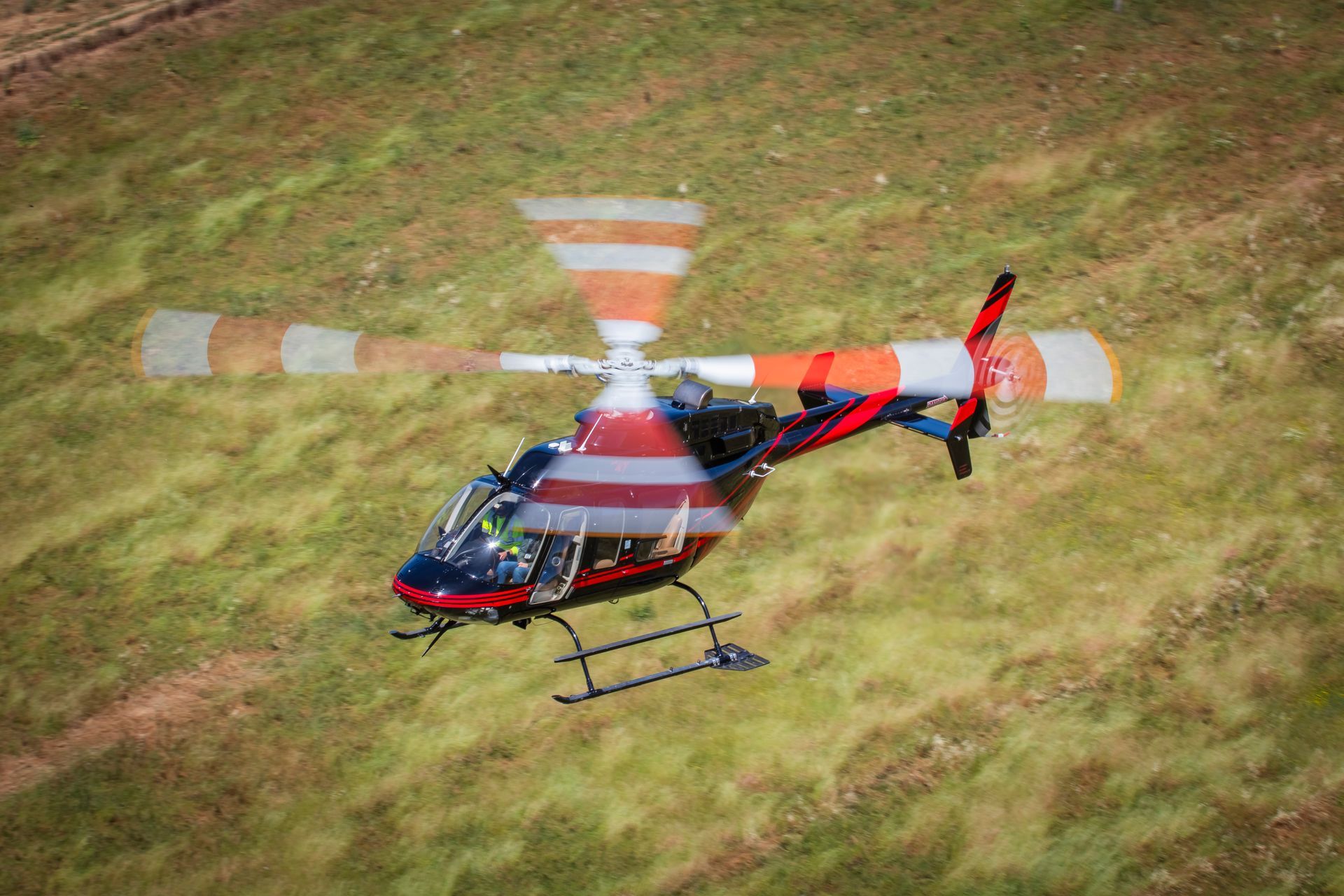 A helicopter is flying over a grassy field.