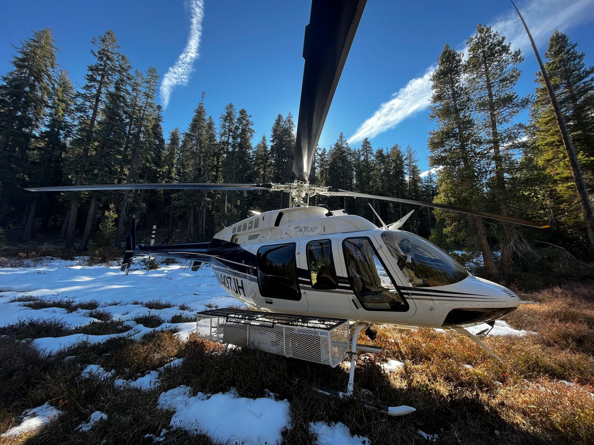 A helicopter is parked in a snowy field with trees in the background
