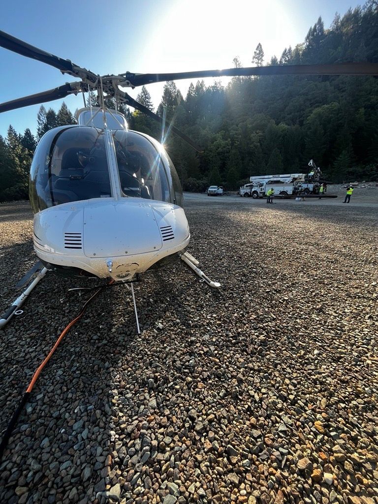 A white helicopter is parked on a gravel field.