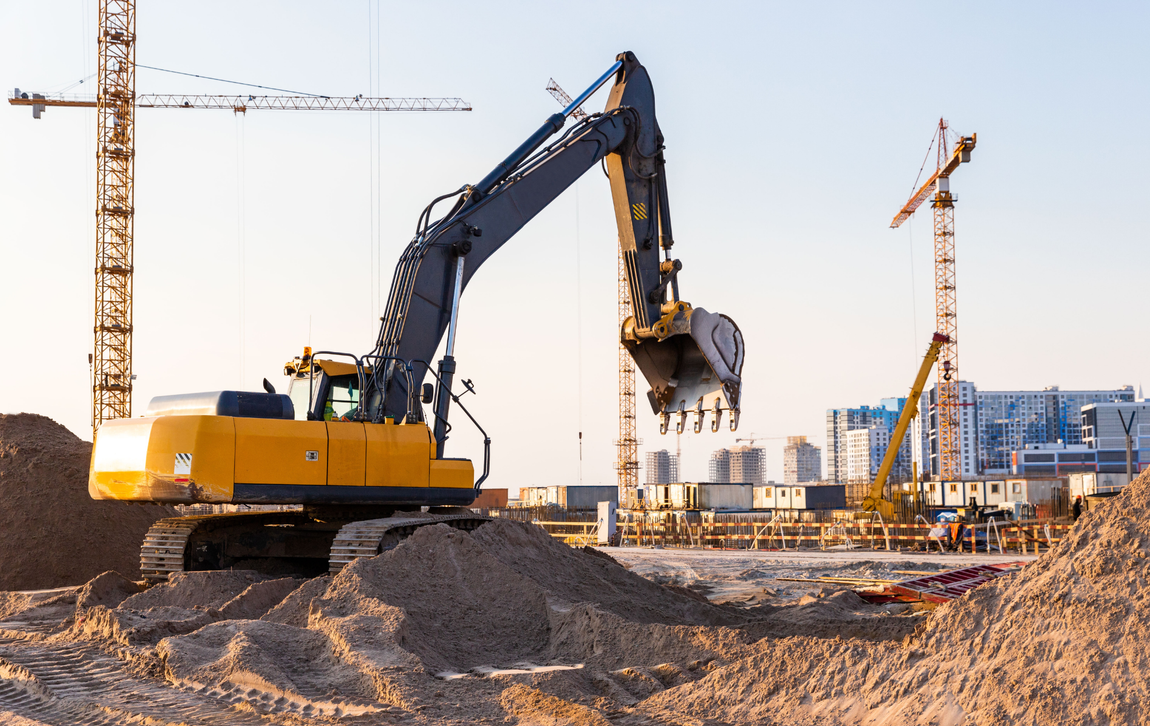 A yellow excavator is digging a hole in a construction site.