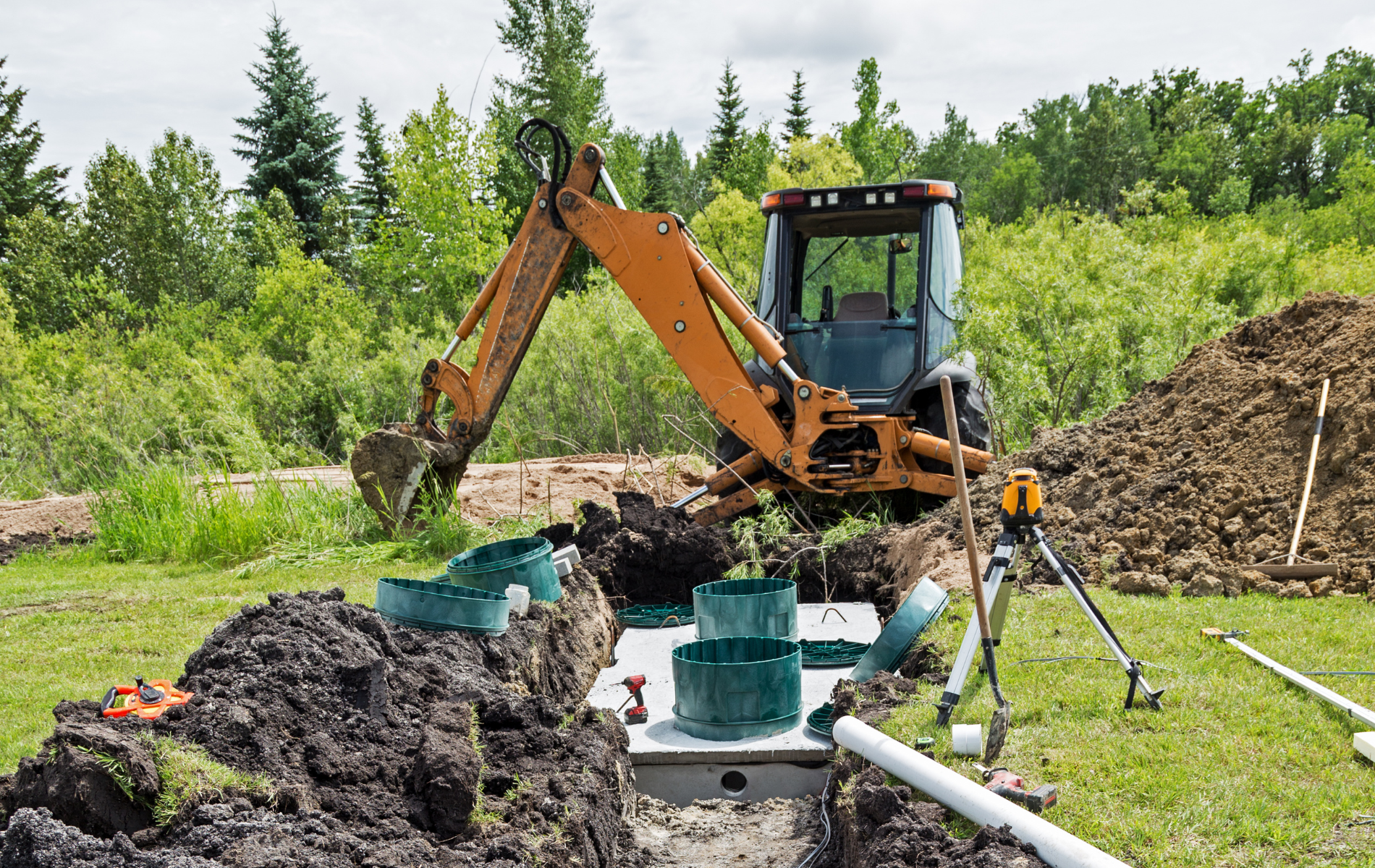 An excavator is digging a septic tank in a field.