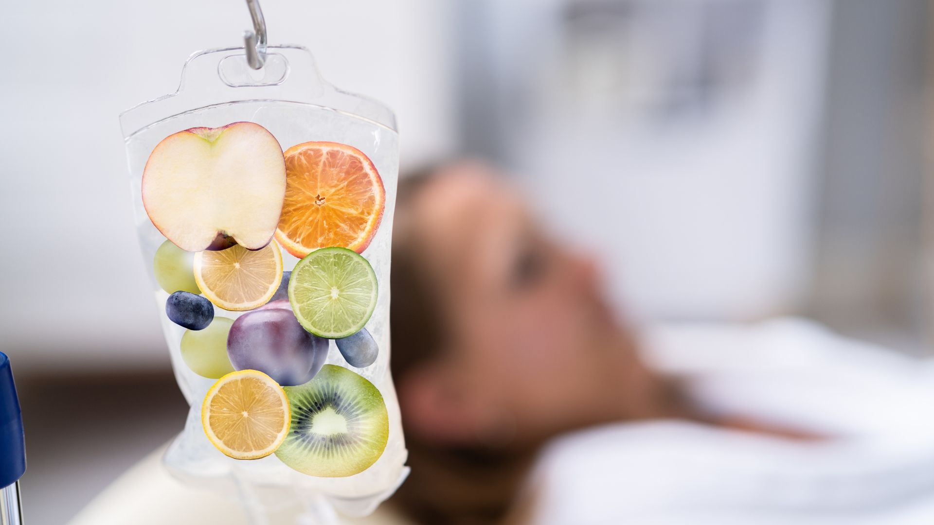 Fruit slices in an IV bag beside a blurred patient in a hospital bed