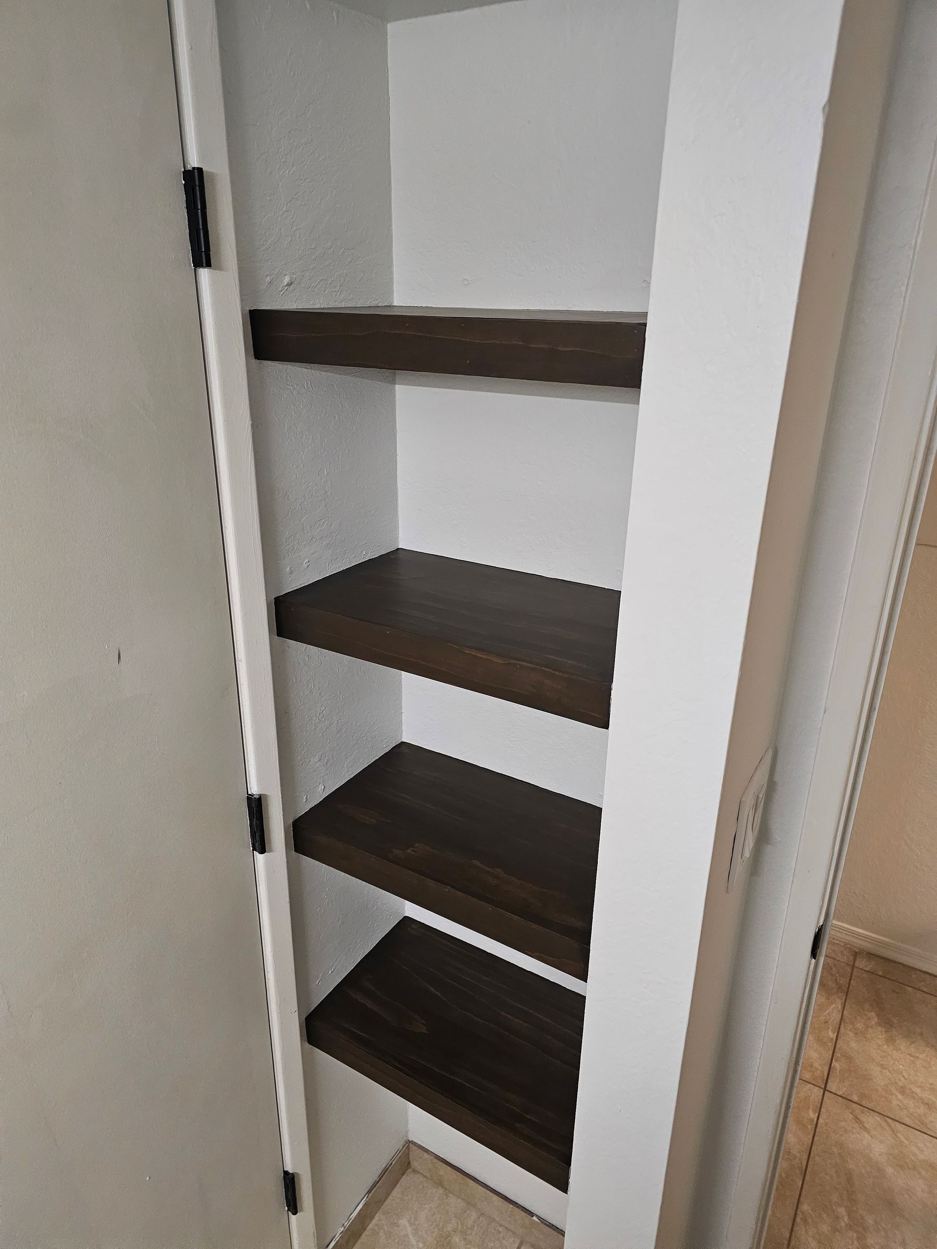 White-framed pantry with dark brown shelves. Empty shelves.