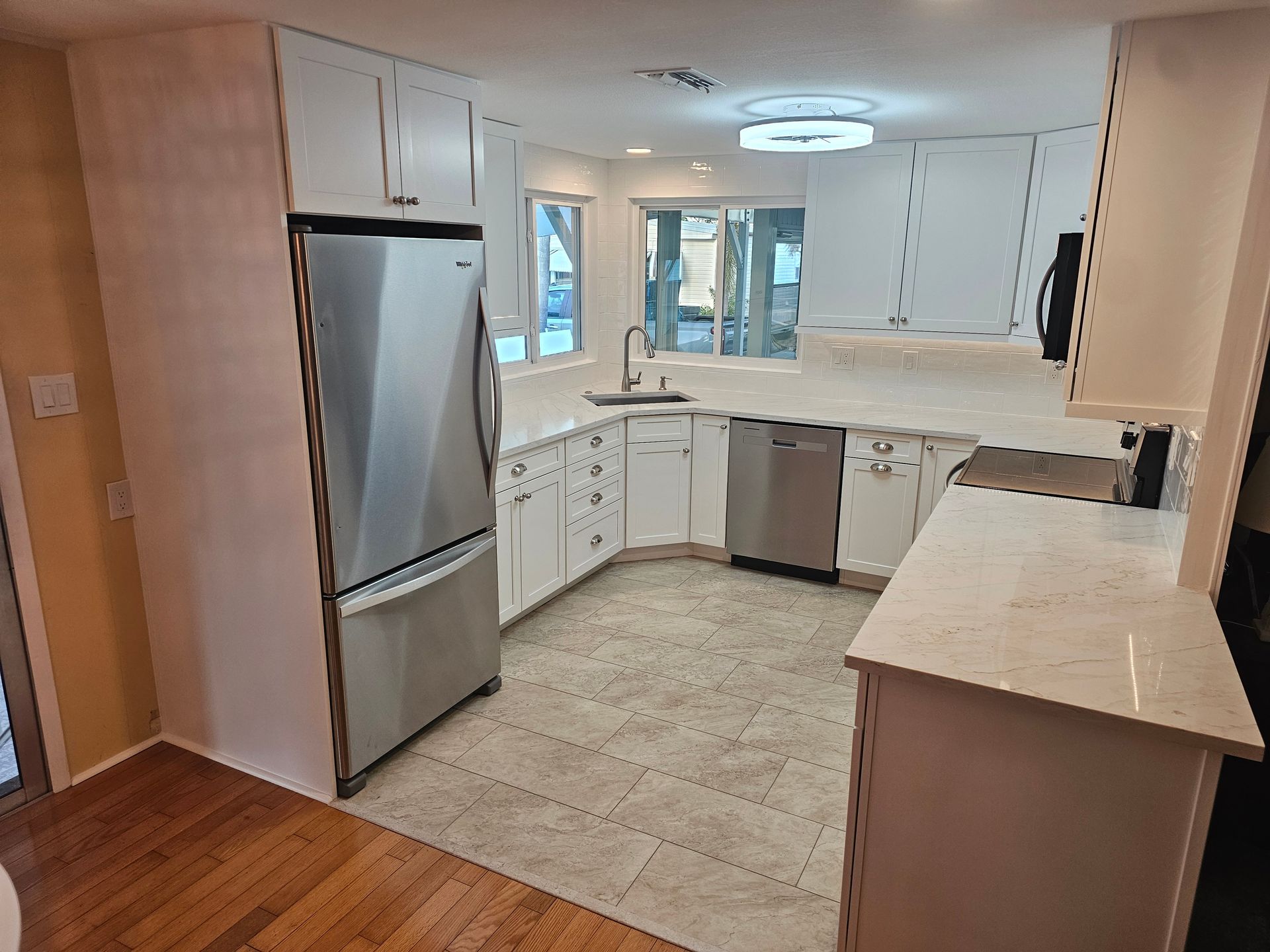 White kitchen with stainless steel appliances, countertops, and cabinets. Window, sink, and dishwasher present.