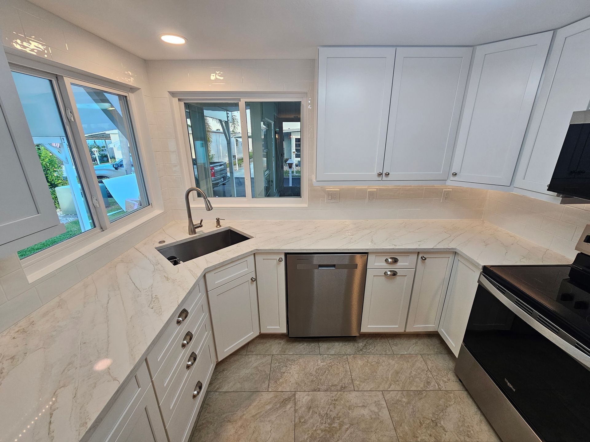 White kitchen with navy blue island, dark wood floor.