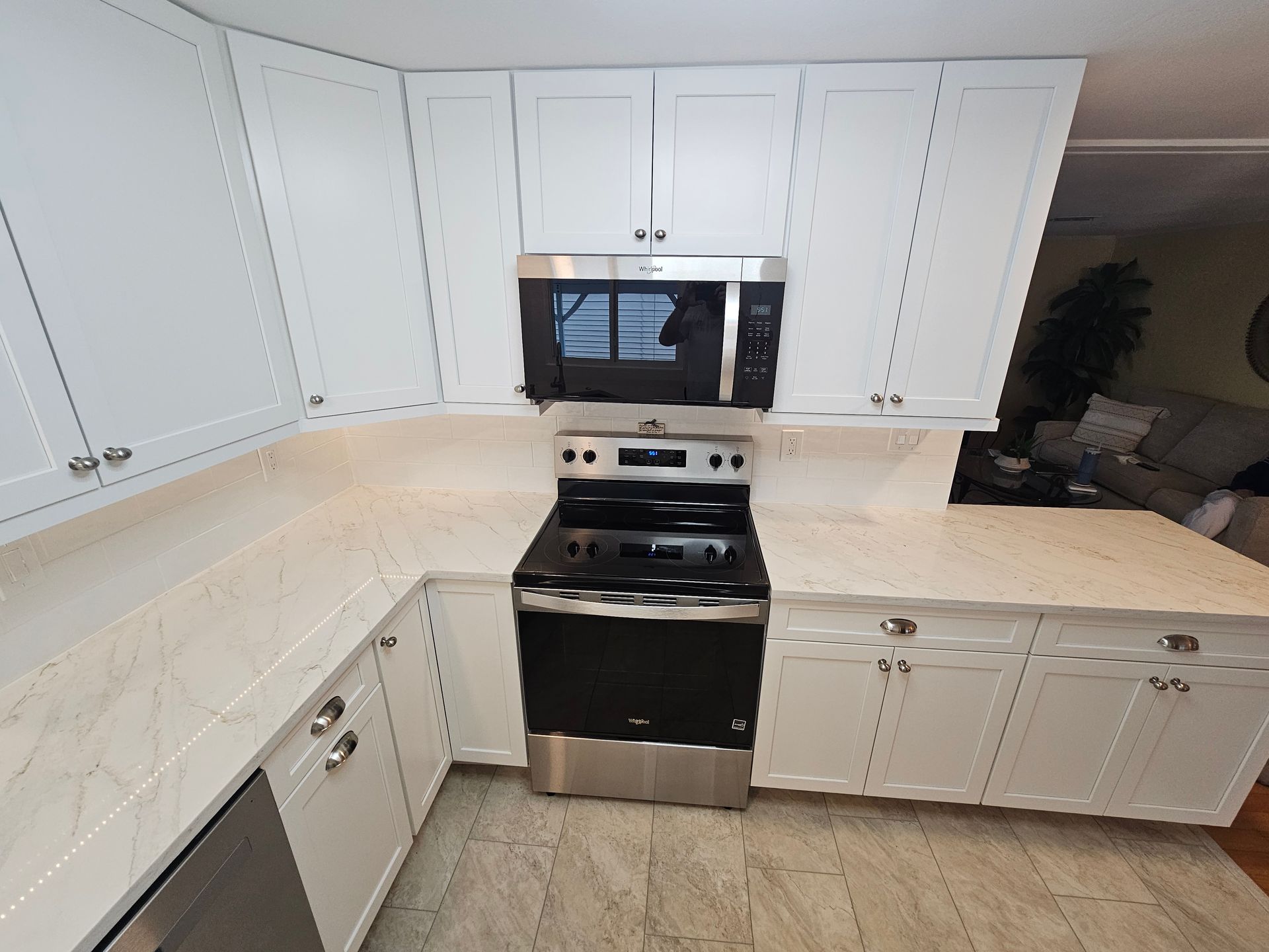 White kitchen with stove, microwave, cabinets, and countertops.