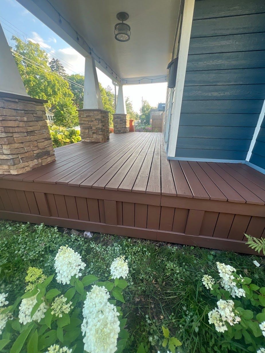 A wooden porch with flowers in front of a house.