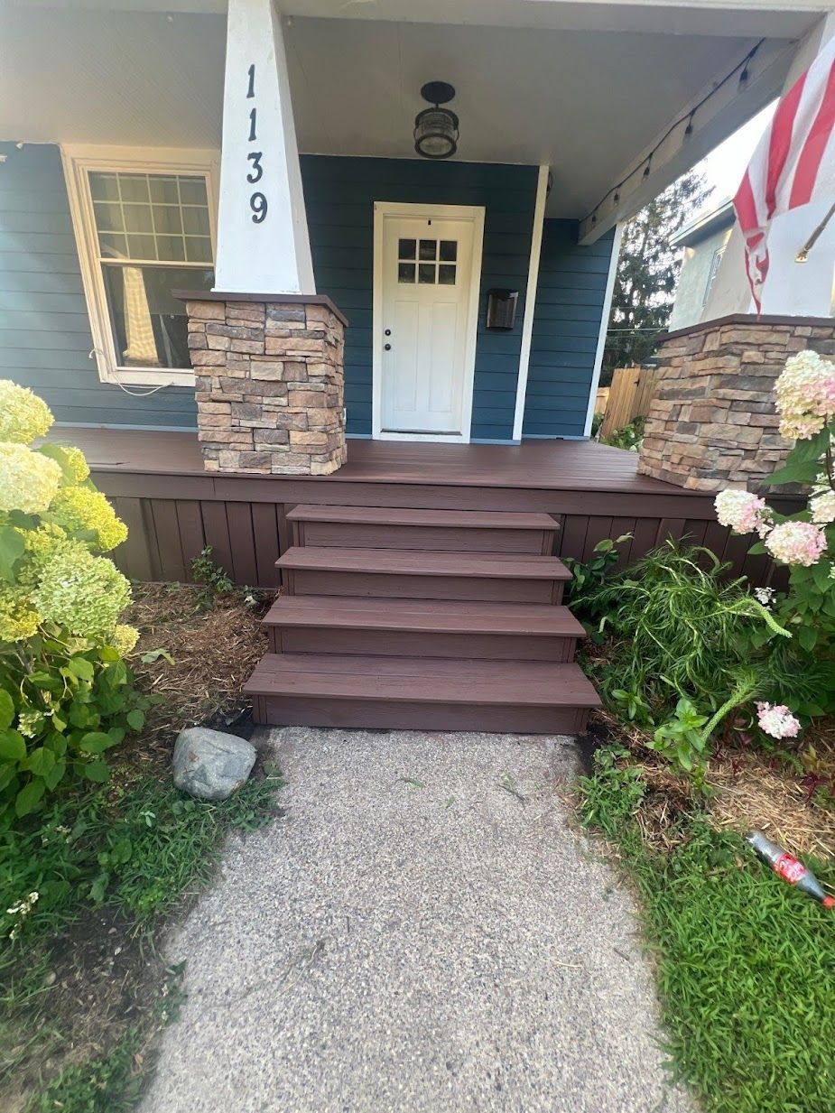 A blue house with a white door and stairs leading up to it.
