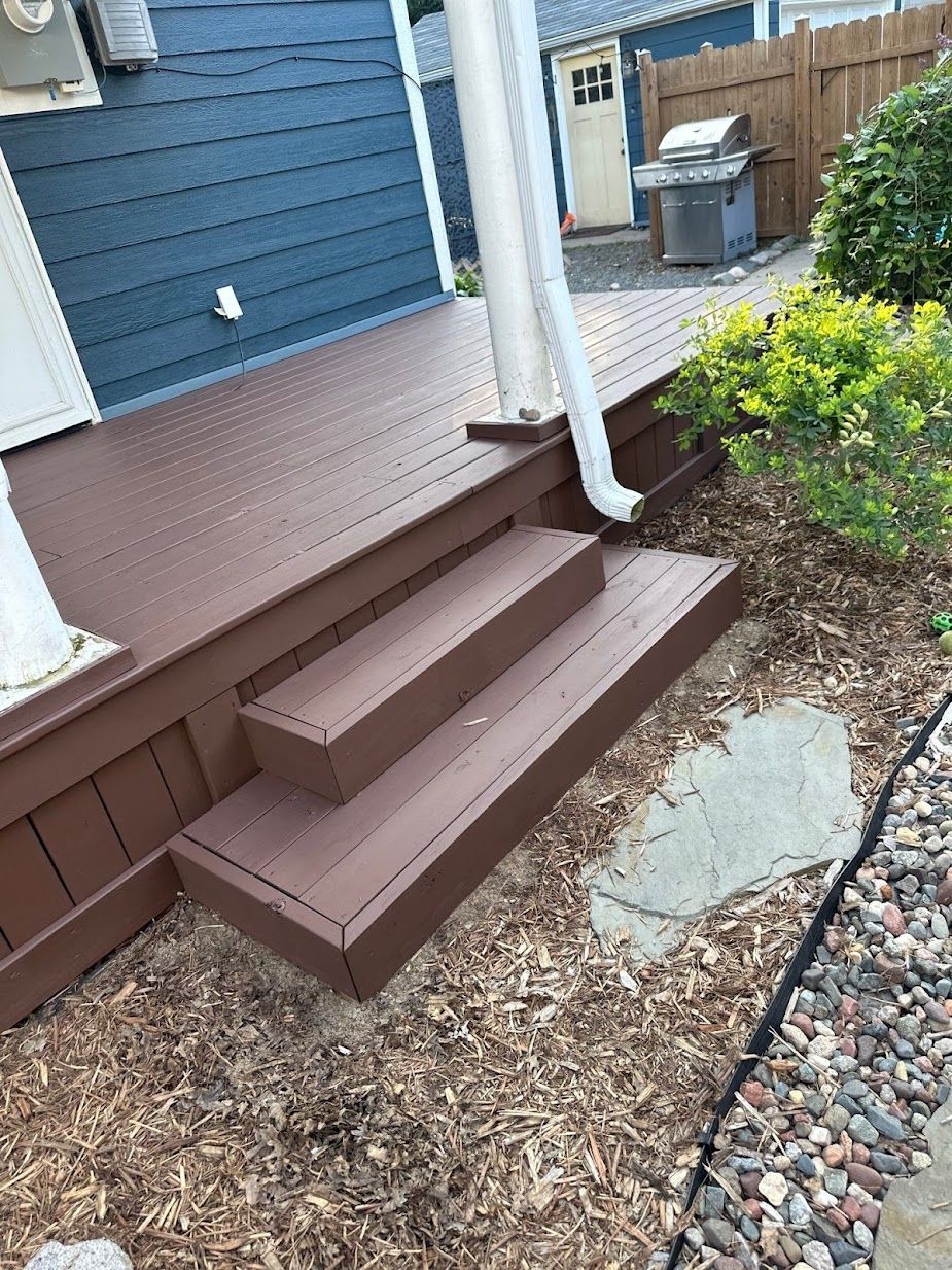 A wooden deck with stairs leading up to it next to a house.