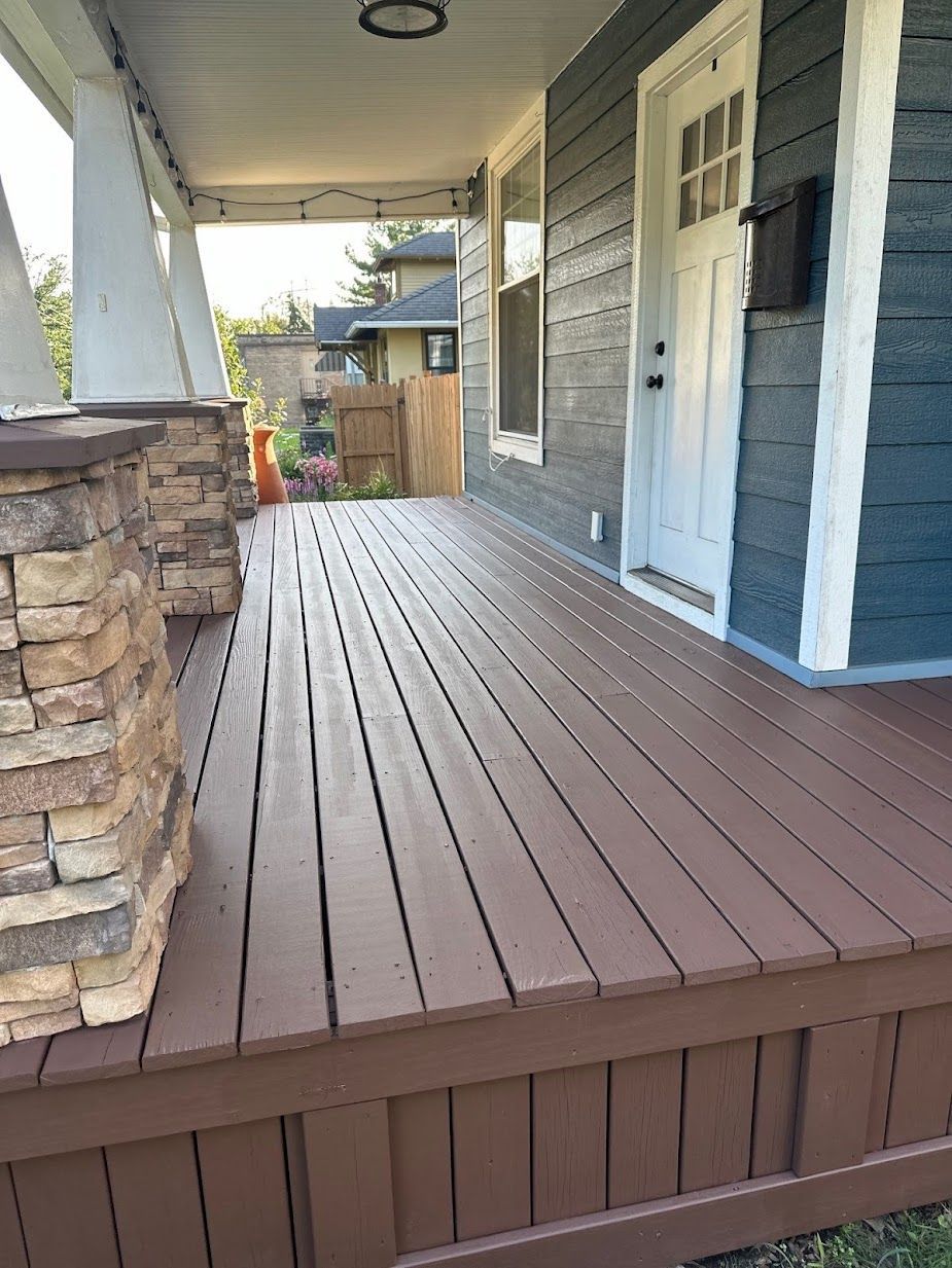 A wooden porch with a stone pillar in front of a house.