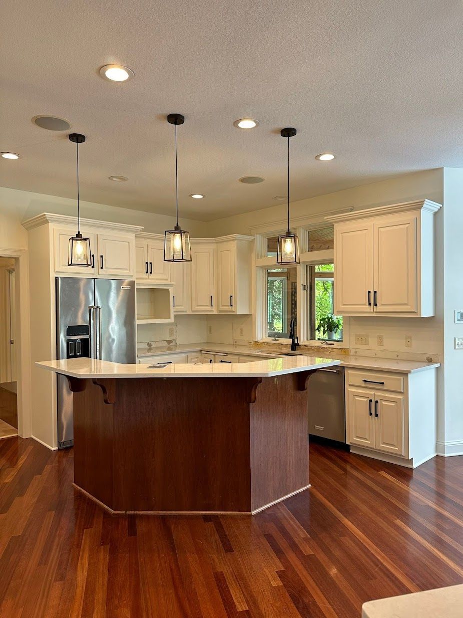 A kitchen with white cabinets , stainless steel appliances , and a large island.