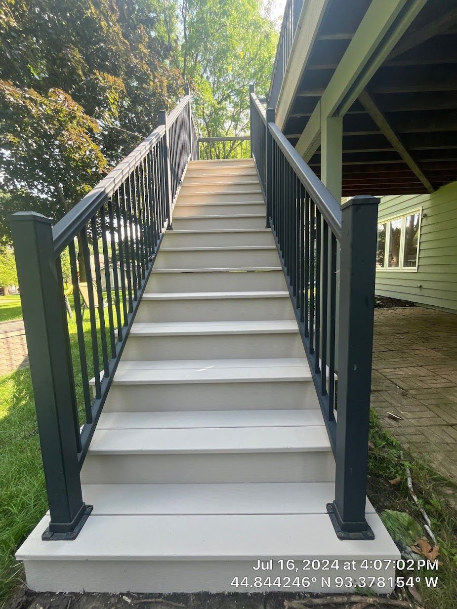 A set of stairs leading up to a deck with a black railing.