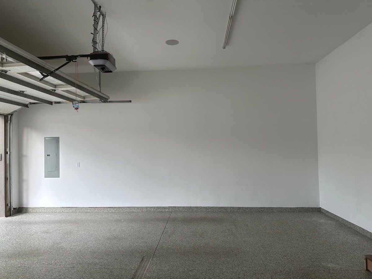 An empty garage with a garage door opener hanging from the ceiling.
