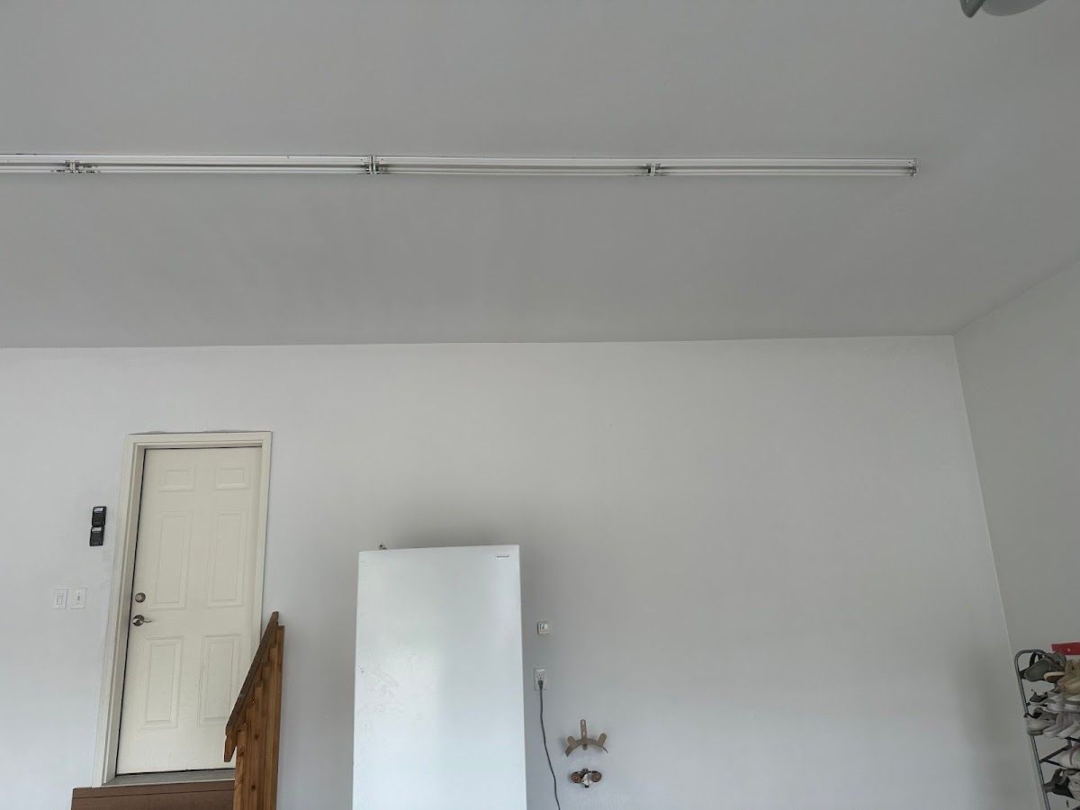 A white wall with a door and a refrigerator in a room.