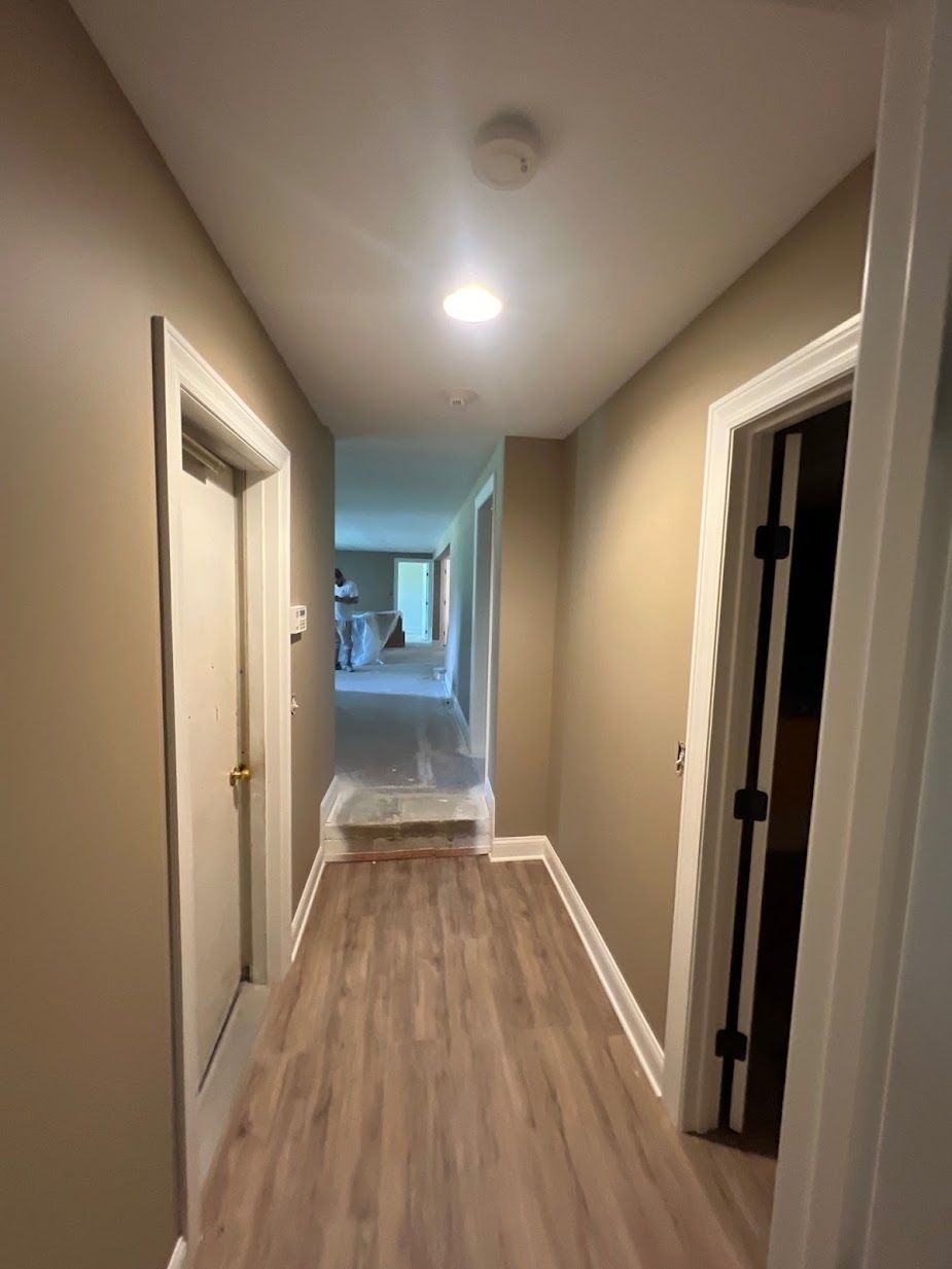 A long hallway with hardwood floors and a ceiling light