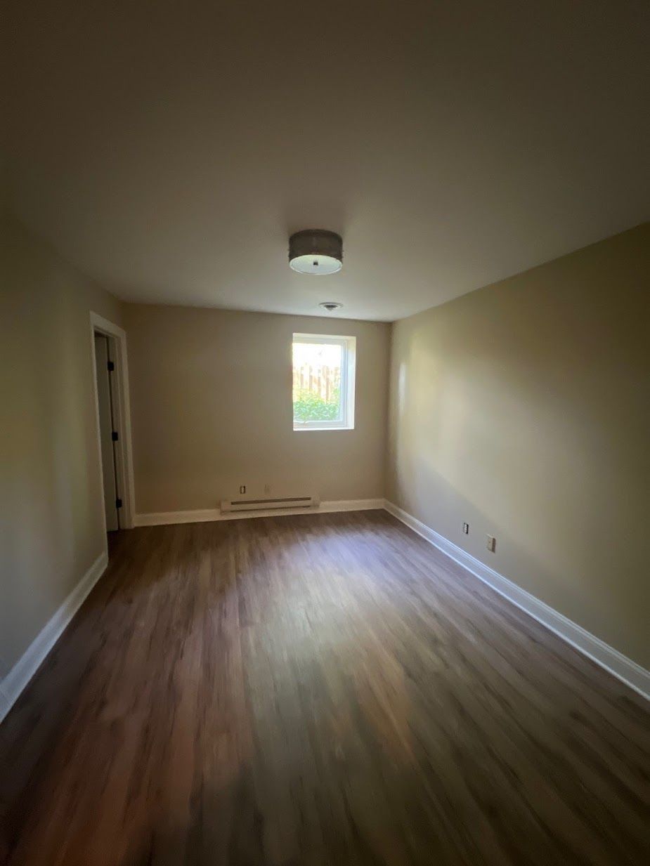 An empty living room with hardwood floors and a window.