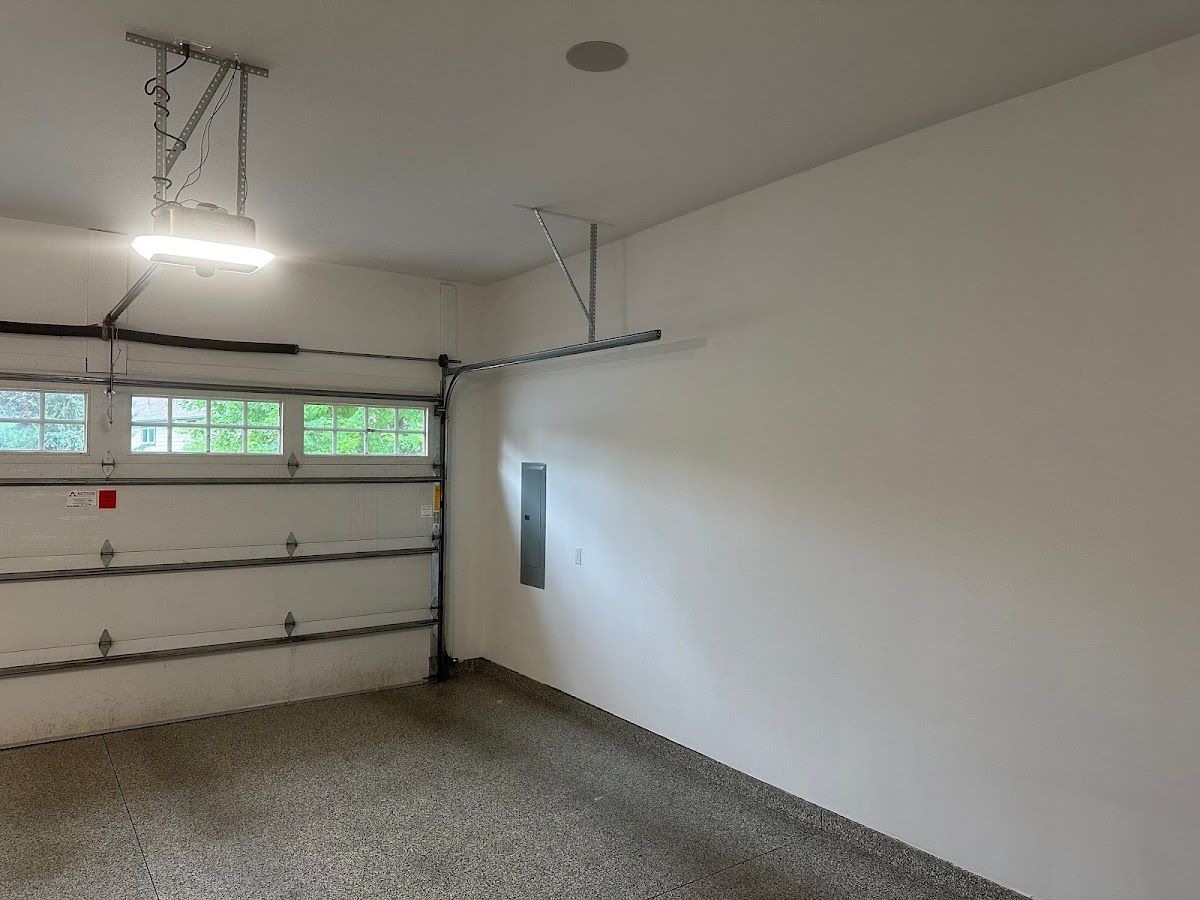 An empty garage with a garage door open and a light on the ceiling.
