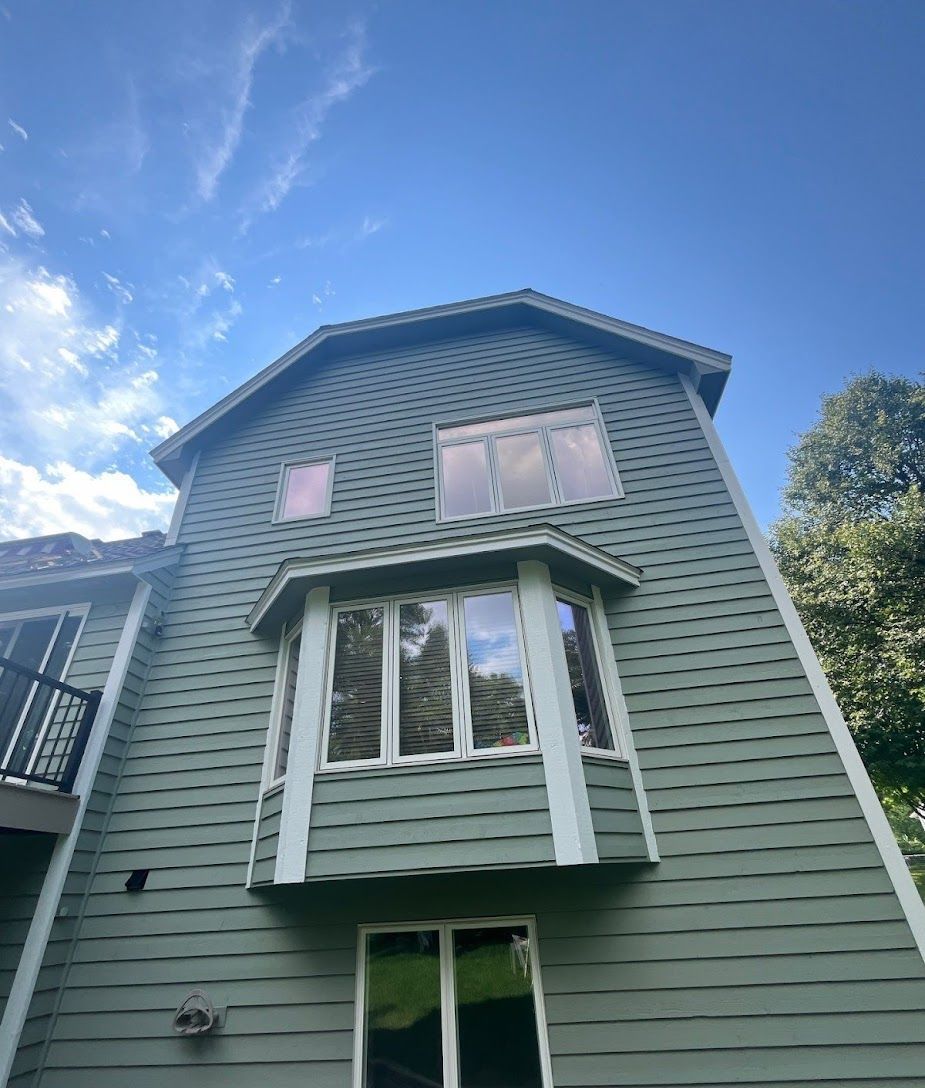 A green house with a lot of windows and a blue sky in the background.
