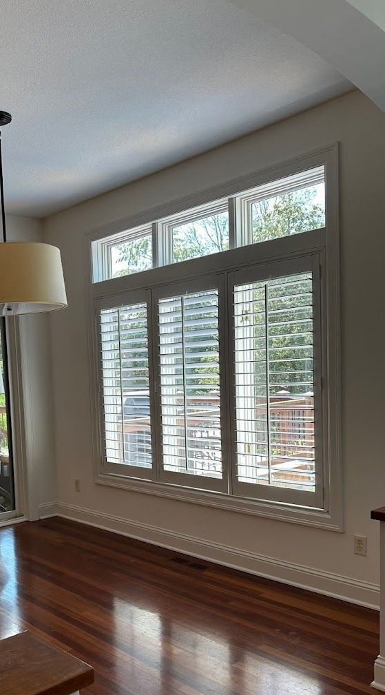 A living room with a lot of windows and a wooden floor.