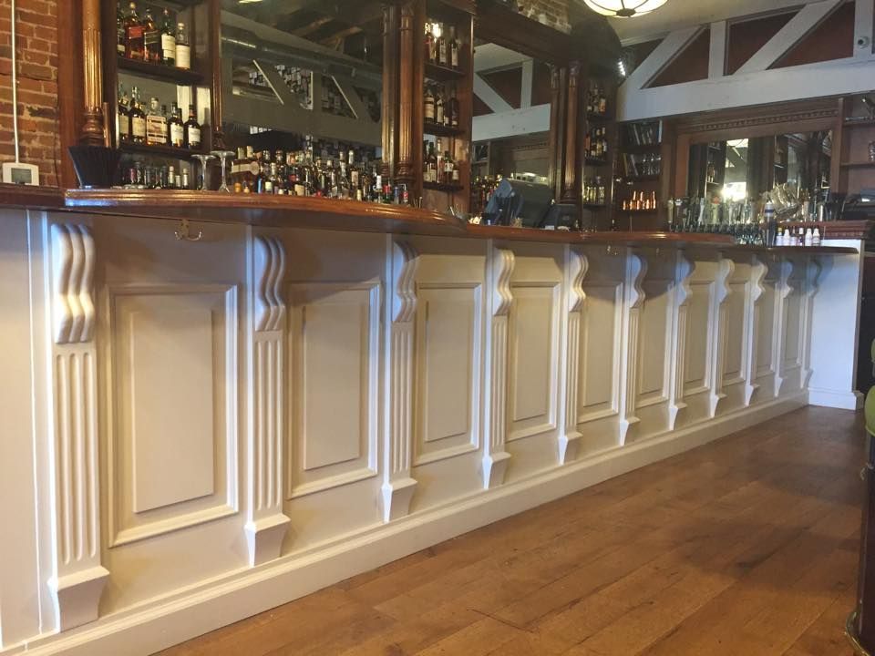 A long white bar in a restaurant with a wooden floor