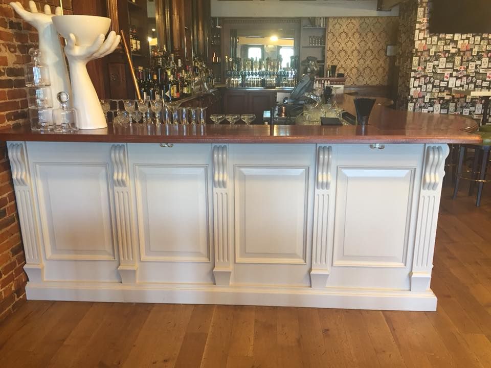 A long white bar with a wooden counter top in a restaurant.