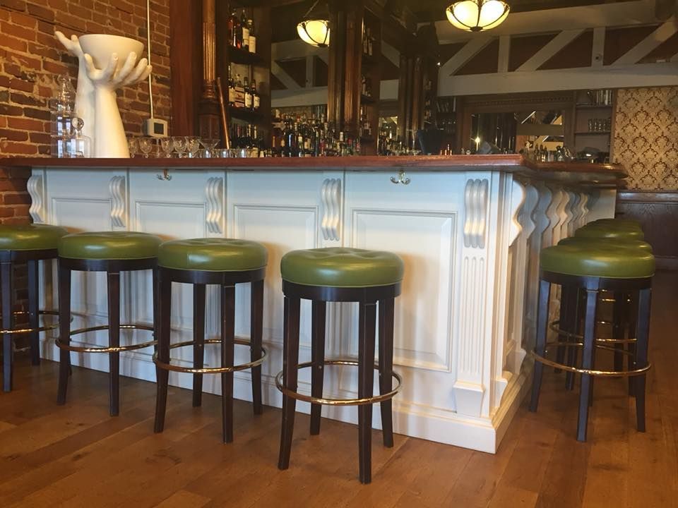 A bar with green stools and a brick wall