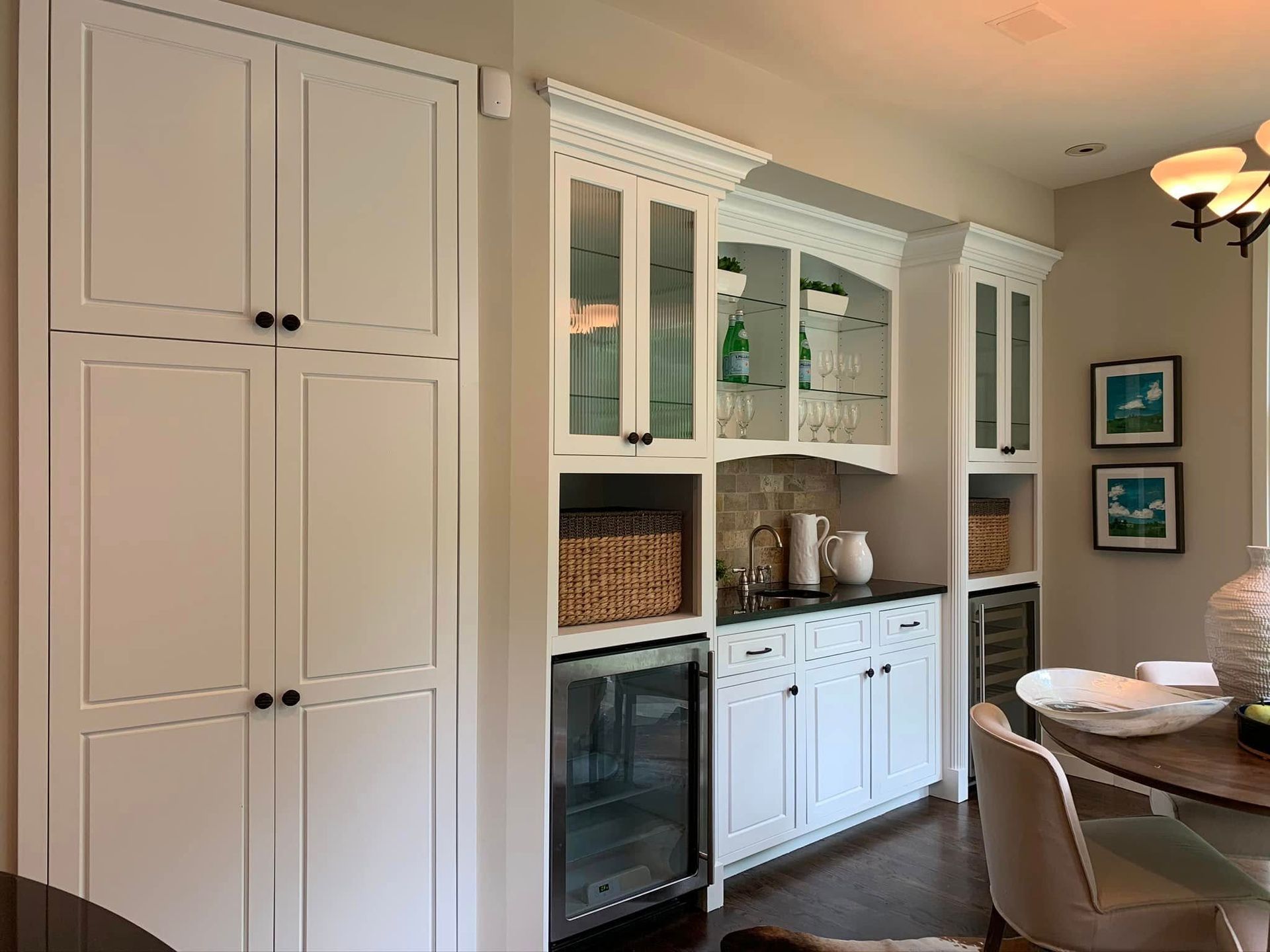 A dining room with white cabinets , a table and chairs.