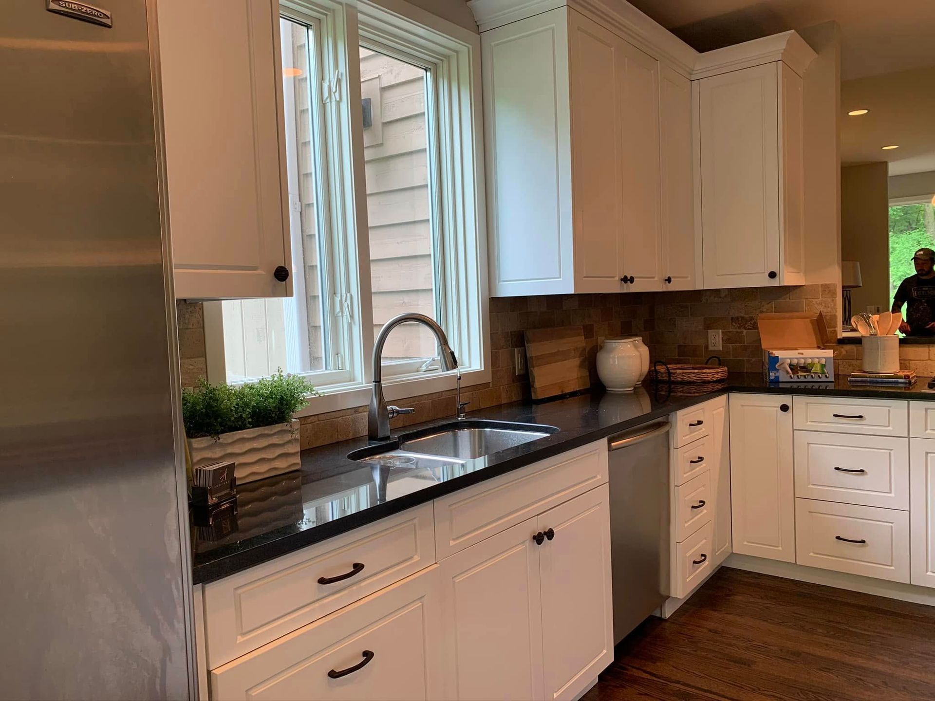 A kitchen with white cabinets , stainless steel appliances , a sink , and a window.